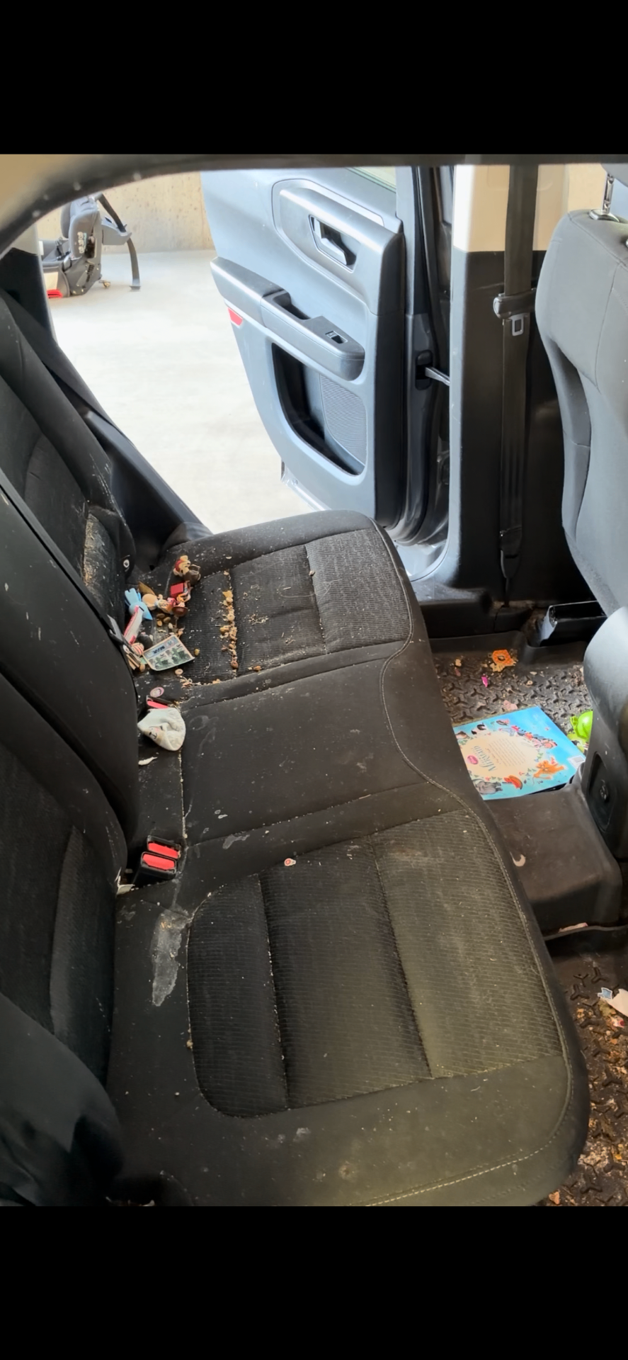 BMW 540i rear fabric seats covered in crumbs, stains, and debris before detailing